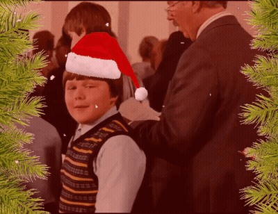 Young Boy In Santa Hat Helped By Man In Suit GIF