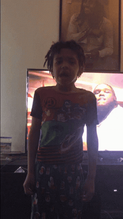 Young Boy In Superhero Shirt In Front Of TV GIF