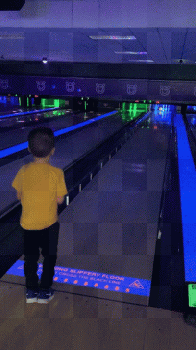 Young Boy In Yellow Shirt With Truck Playing Bowling GIF