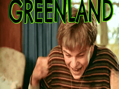 Young Boy Laughing in Front of Greenland Sign