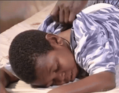 Young Boy Lying On Bed With Hand On Neck GIF