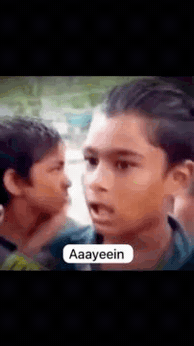 Young Boy Making Funny Face To Another In Crowd GIF