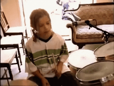 Young Boy Playing Drums In Living Room With Microphone GIF