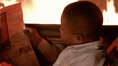 Young Boy Reading Newspaper In Car With Fire GIF