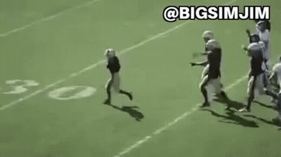 Young Boy Running on Football Field With Players