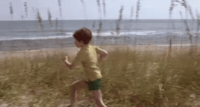 Young Boy Running On Sandy Beach GIF