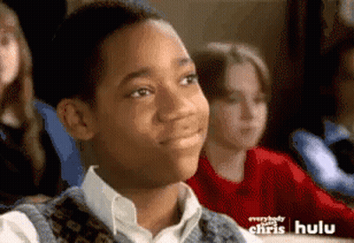 Young Boy Sitting In Classroom With Hulu Ad Behind Him GIF