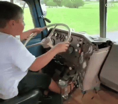 Young Boy Sitting In Driver Seat Of Bus GIF