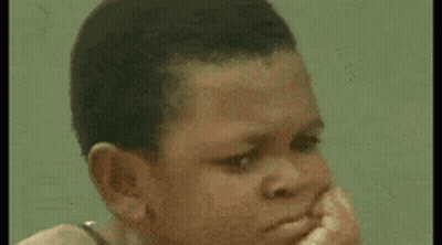 Young Boy Sitting On Rock At Beach Looking At Camera GIF