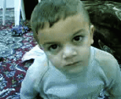 Young Boy Sitting On Rug Looking At Camera GIF