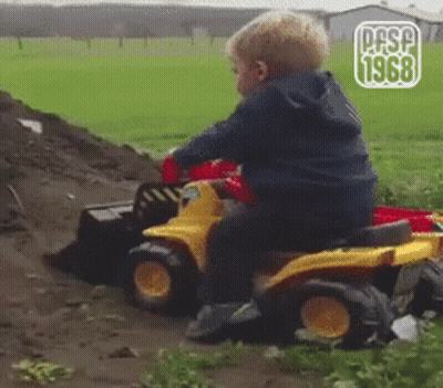 Young Boy Sitting On Toy Bulldozer In Field GIF