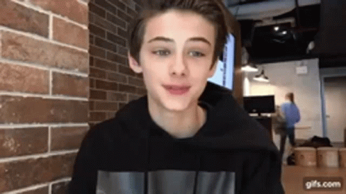 Young Boy Smiling In Front Of Brick Wall GIF