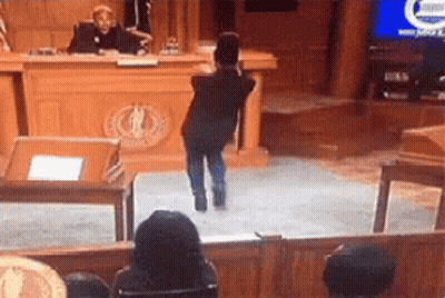 Young Boy Standing Before Judge In Courtroom GIF