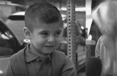 Young Boy Standing Next To Shelf Black And White GIF