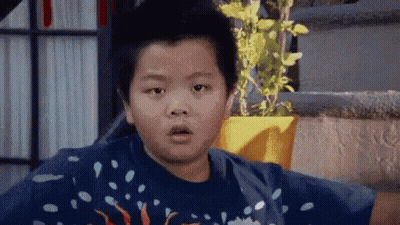 Young Boy Surprised Beside Potted Plant GIF