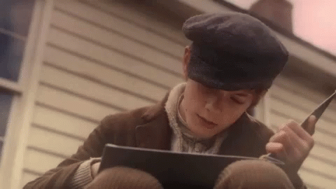 Young Boy Wearing Hat Reading Book On Ground GIF