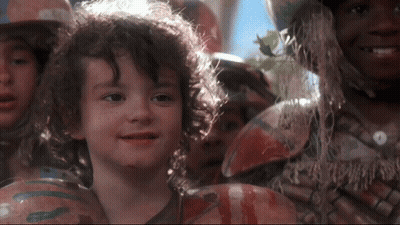 Young Boy With Curly Hair Smiling In Front Of Crowd GIF