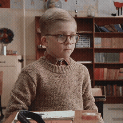 Young Boy With Glasses Sitting At Desk In Classroom GIF