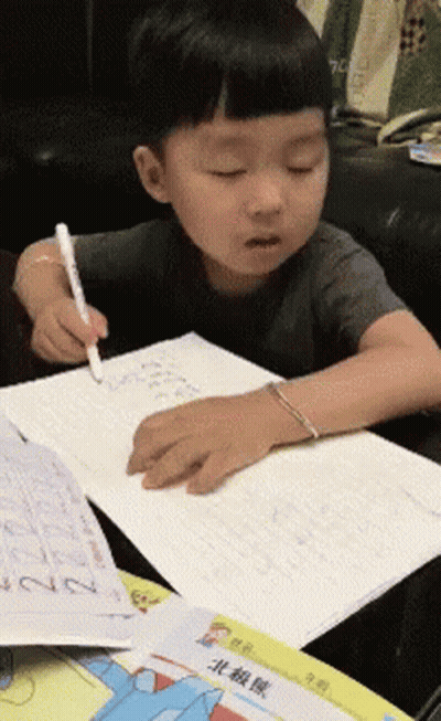Young Boy Writing In Notebook At Table GIF