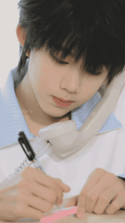 Young Boy Writing on Paper While Talking on Phone
