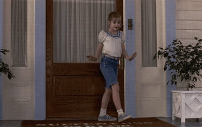 Young Girl At Door With Welcome Rug GIF