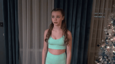 Young Girl In Green Sports Bra In Front Of Christmas Tree GIF