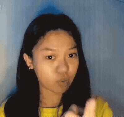 Young Girl In Yellow Shirt Pointing With Funny Face GIF