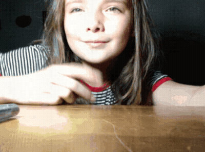 Young Girl Sitting At Table With Remote Control GIF