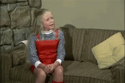 Young Girl Sitting On Couch With Yellow Pillow GIF