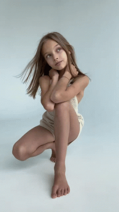 Young Girl Squatting With Legs Crossed Looking Up GIF
