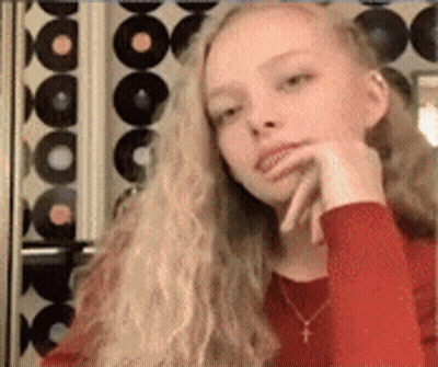 Young Girl With Long Blonde Hair And Red Shirt And Necklace GIF