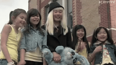 Young Girls Holding Hands Smiling In Front Of Brick Building GIF