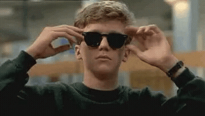 Young Man Adjusting Sunglasses In Library GIF