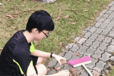 Young Man Cleaning Ground With Pink Broom GIF