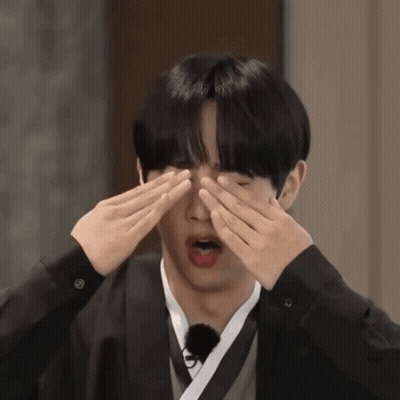 Young Man Covering Eyes in Black Jacket