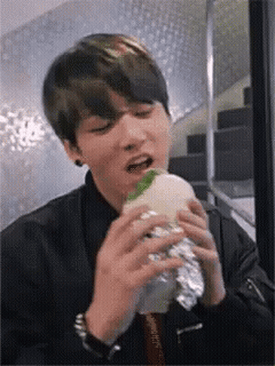 Young Man Eating Foil-Wrapped Hamburger GIF