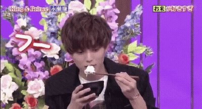 Young Man Eating Rice And Using Phone Beside Flowers GIF
