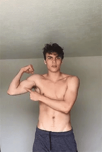 Young Man Flexing Muscles And Pointing At Arm GIF