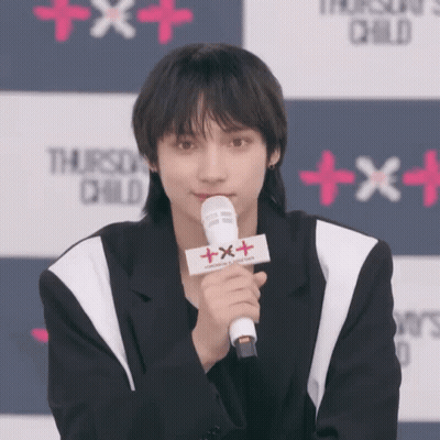 Young Man Holding Microphone With Sign Saying Txxx GIF
