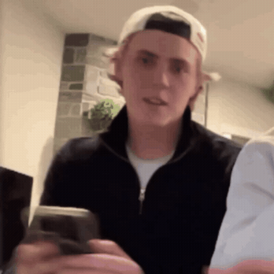 Young Man In Baseball Cap Holding Cell Phone GIF