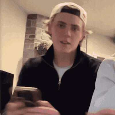 Young Man In Baseball Cap Holding Cellphone GIF