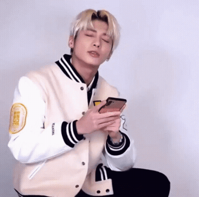 Young Man In Baseball Jacket Holding Cell Phone GIF