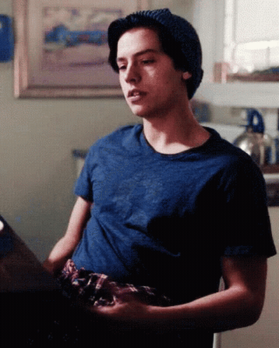 Young Man In Beanie And Blue Shirt Sitting GIF