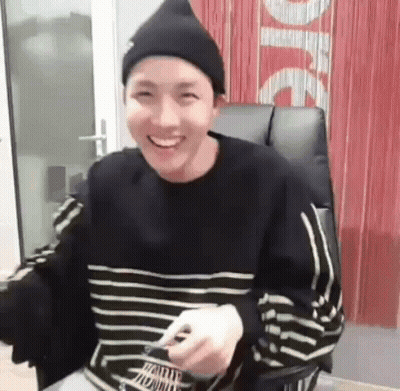 Young Man In Beanie And Striped Shirt Sitting GIF