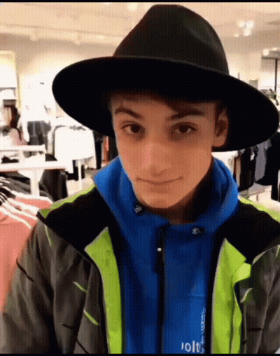Young Man In Black Hat And Blue Jacket Looking At Camera GIF