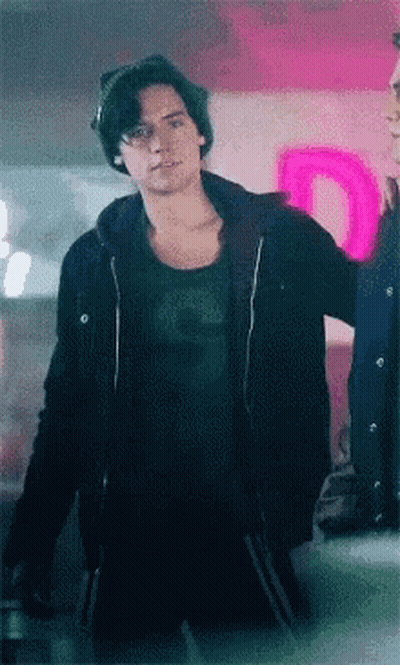 Young Man In Black Jacket And Beanie In Front Of Neon Sign GIF