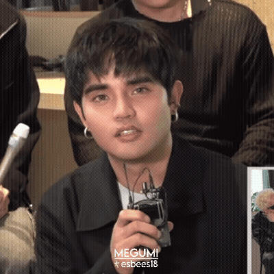 Young Man In Black Jacket And Earrings Holding Microphone And Cell Phone GIF