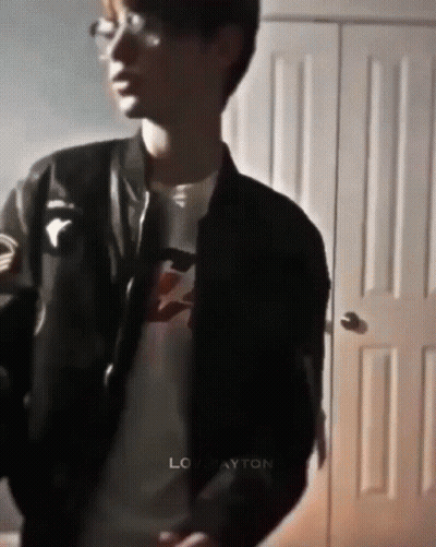 Young Man In Black Jacket And Glasses By Door GIF