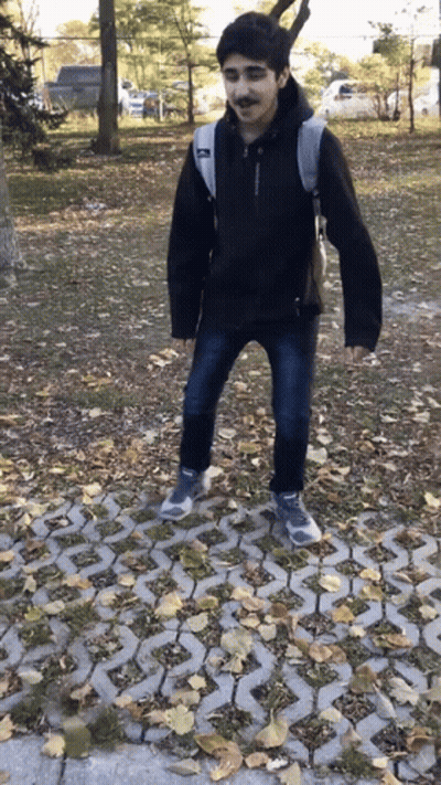 Young Man In Black Jacket With Backpack On Brick Walkway GIF