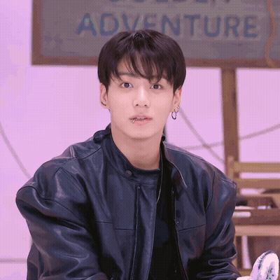 Young Man In Black Leather Jacket And Earrings In Front Of Adventure Sign GIF